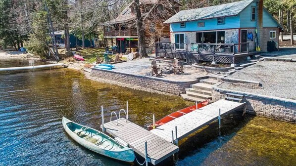 Una baita sul lago con un molo, una barca e una terrazza coperta.