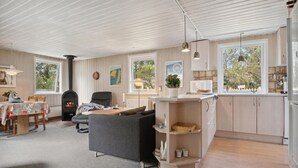 A modern living room with a fireplace, a sofa, and a dining area with a table and chairs.