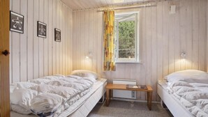 A room with two beds, a small table, and a window with curtains.
