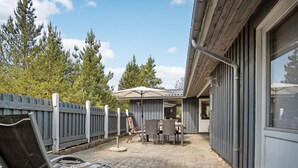 An outdoor patio area with a wooden fence, a covered seating area, and a brick floor.