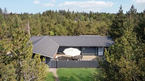 A house with a sloped roof, a fenced yard, and a patio with outdoor furniture.