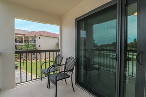 Enjoy the view from this balcony with a sliding glass door, two comfortable chairs, and a small outdoor space.