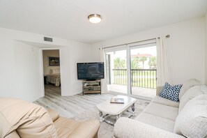 Relax in this stylish living room with a flat-screen TV, comfortable sofa, and sliding glass door leading to a balcony.