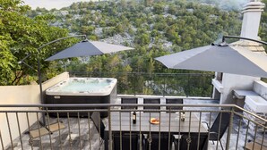 Eine Dachterrasse mit Whirlpool, Sitzgelegenheiten im Freien und einem schönen Ausblick auf eine bewaldete Hügellandschaft.