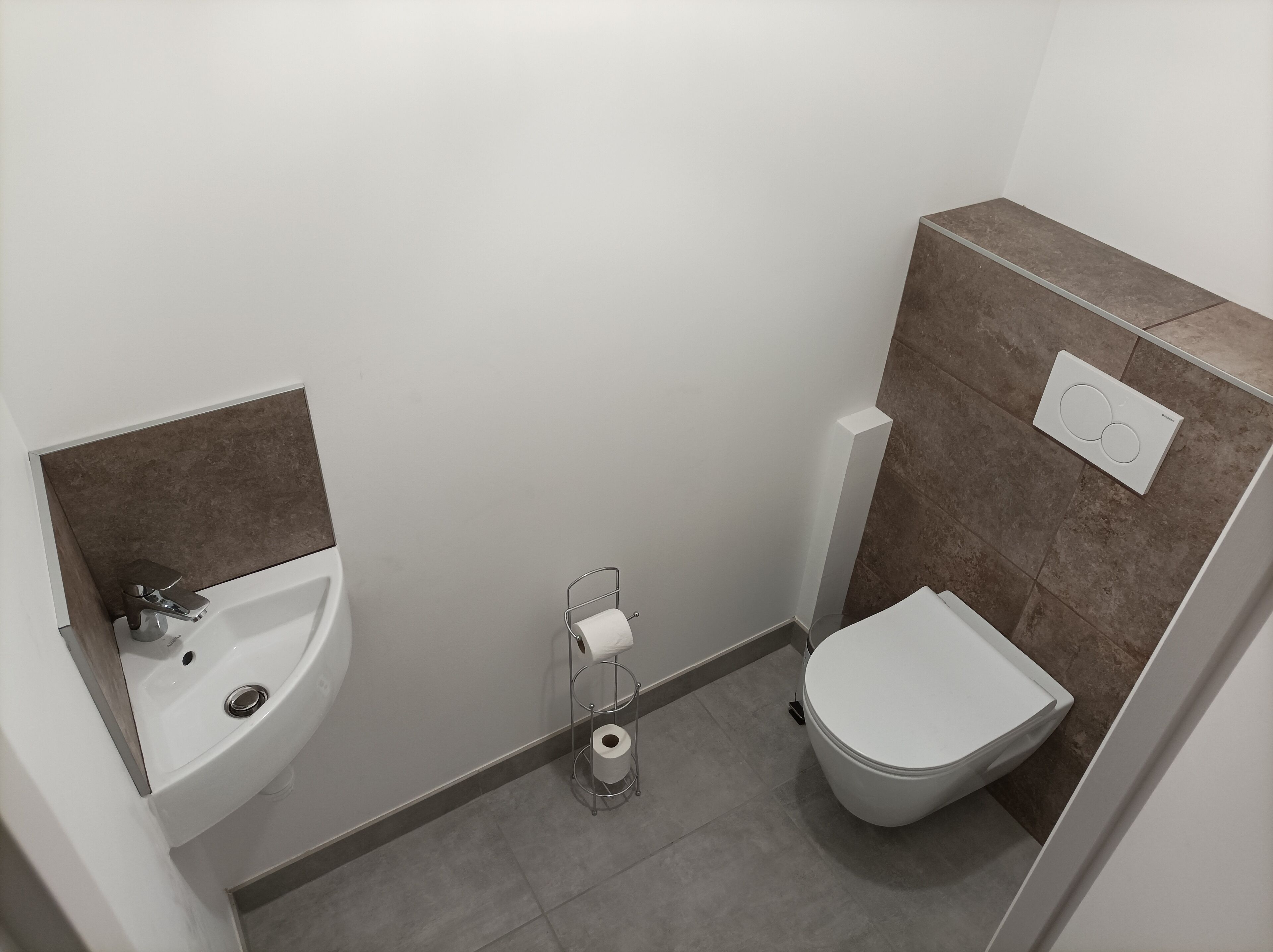 A compact bathroom with a sink, toilet, and a towel rack.