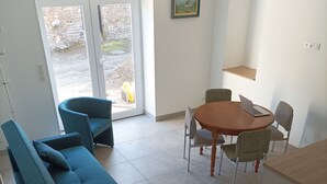 Un salon moderne comprenant un ensemble de canapés, une table à manger avec des chaises et un coin cuisine.