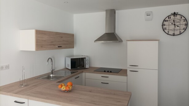 Une cuisine moderne équipée d’un four à micro-ondes, d’un évier et d’un plan de travail en bois.