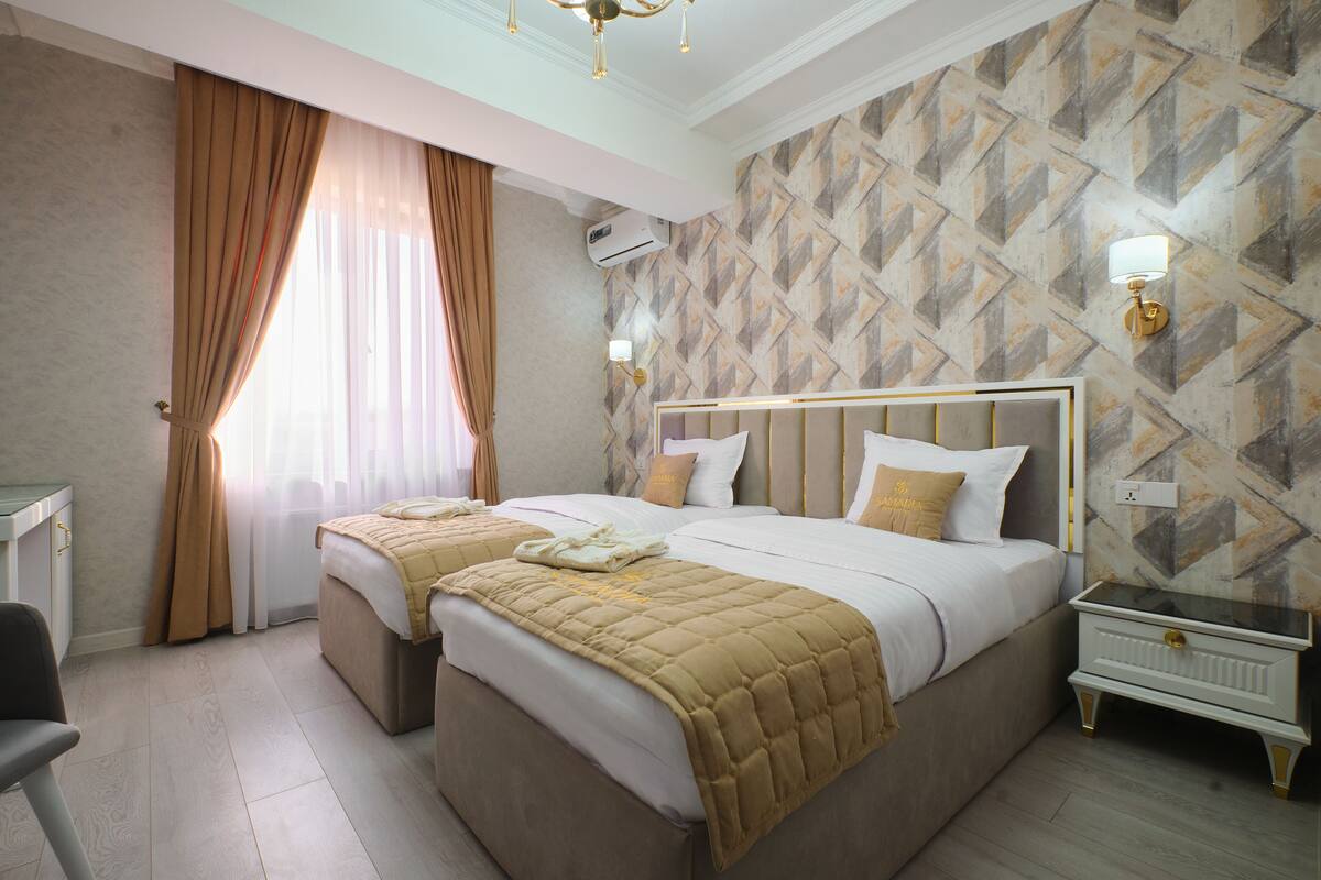 Habitación de hotel con dos camas, un escritorio y una mesita de noche.