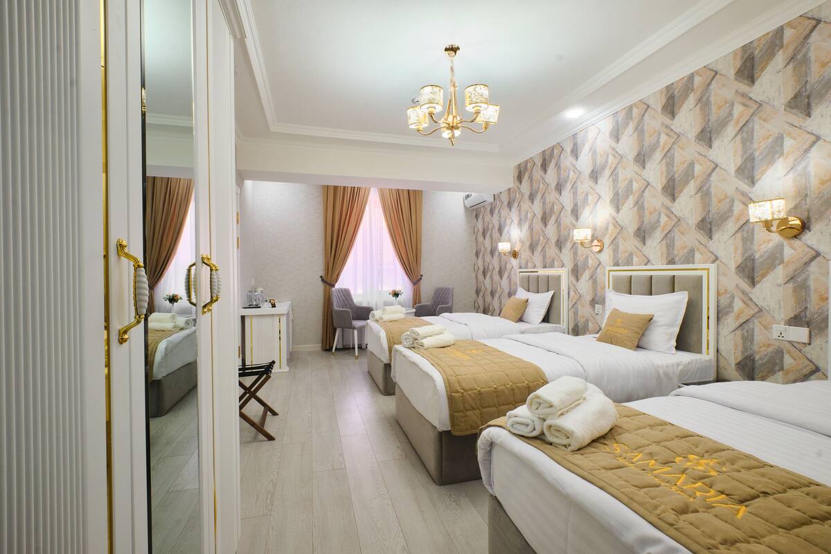 Una habitación de hotel con tres camas, un escritorio y un espejo.