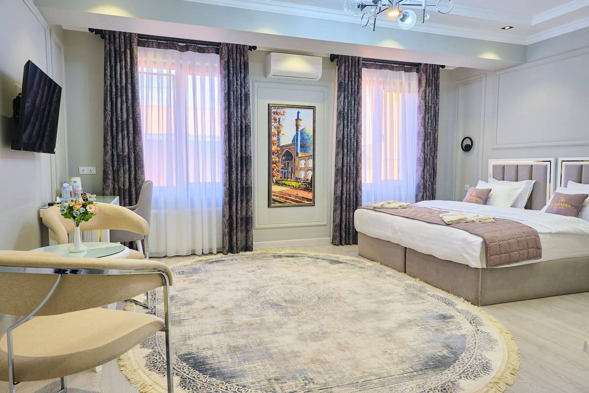 Una habitación de hotel con una cama, una silla, una mesa y un cuadro en la pared.