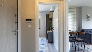 En modern inredning med ett matområde, en soffa och ett kök i bakgrunden.