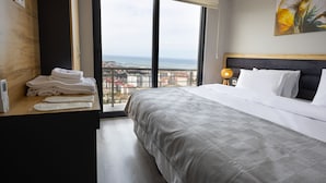 Ett hotellrum med en stor säng, utsikt över staden och ett skrivbord i trä med handdukar.