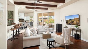 A spacious living area with a sofa, coffee table, and chairs, a ceiling fan, and a large window with a view. - Private Mini-Resort w/ Salt water pool & spa- NEW! (Scottsdale)