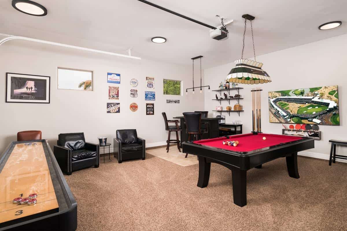 A billiards room with a pool table, a shuffleboard table, and a dartboard.