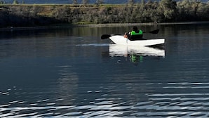 A kayaker in a white kayak on a calm lake with mountains in the background. - Glamping Svetlyi Mys (Ak-Bulun)