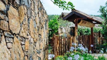 Un muro de piedra rústico con una valla de madera y una estructura de techo de paja.