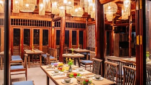 Um restaurante com mobiliário de madeira, luminárias pendentes e decoração asiática tradicional.