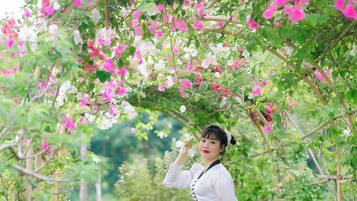 A woman standing under a floral archway in a garden.