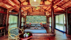 Um quarto espaçoso com uma cama grande, teto de madeira e parede de pedra.