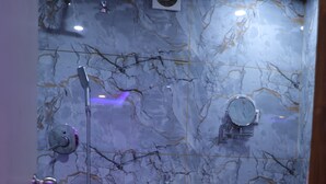 A bathroom with a marble wall, a sink, a toilet, and a shower. - kapila residency (Bengaluru)