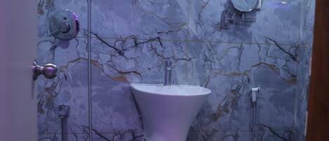 Un bagno con parete in marmo, lavandino, water e doccia.
