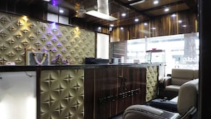 A reception area with a wooden panel design, a counter, and a seating area with a leather couch. - kapila residency (Bengaluru)