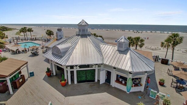 A beachside building with a pool, outdoor seating, and a view of the beach. - Steps to Two Oceanfront Pools | Walk to Dining | Grand Pavilion (Isle of Palms)
