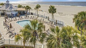 A beachside resort with a pool, lounge chairs, and a bar area. - Steps to Two Oceanfront Pools | Walk to Dining | Grand Pavilion (Isle of Palms)