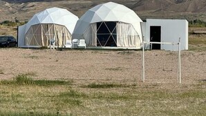Dos tiendas de campaña con forma de cúpula en un paisaje árido y abierto, con montañas al fondo.