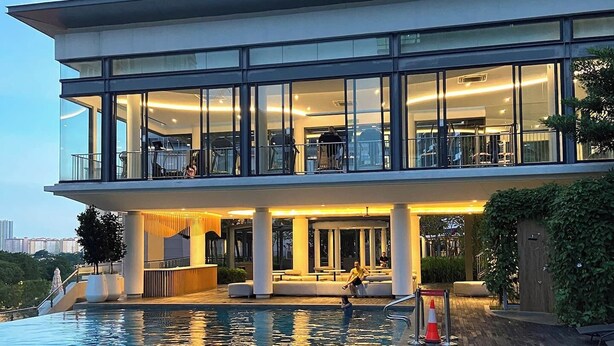 A modern hotel with a pool area, featuring a glass facade, outdoor seating, and a view of the city skyline. - "La Gente", The People (rakyat) in Spanish, represents our dedication and passion to serve our guests and meet interesting souls. (Kuala Lumpur)