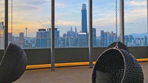 A view from a high-rise building with hanging chairs and a cityscape in the background. - "La Gente", The People (rakyat) in Spanish, represents our dedication and passion to serve our guests and meet interesting souls. (Kuala Lumpur)