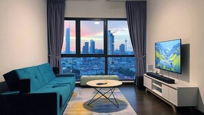 A modern living room with a city view, a sofa, a coffee table, a TV, and a ceiling fan. - "La Gente", The People (rakyat) in Spanish, represents our dedication and passion to serve our guests and meet interesting souls. (Kuala Lumpur)