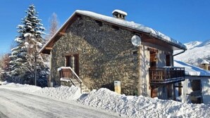 Ein Steingebäude mit schneebedecktem Dach, einer Holztreppe und einer Satellitenschüssel.