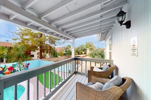 A covered outdoor area with wicker furniture and a pool. - Fun-filled, modern home with game room, heated pool, hot tub, grill (Chandler)