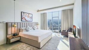 A modern hotel room with a large bed, bedside tables with lamps, a desk with a chair, and a large window offering a city view. - FARHAN TOWER (Manama)