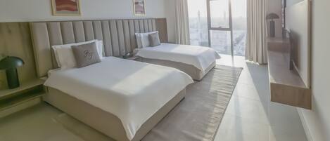 A modern hotel room with two beds, a large window with a city view, and a flat-screen TV mounted on the wall.