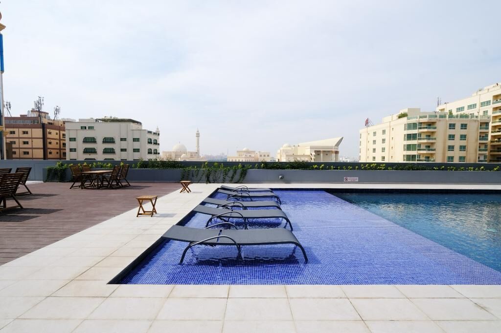 Un espace piscine aménagé sur le toit, avec des chaises longues et une vue sur les bâtiments environnants.