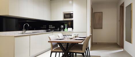 A modern kitchen with a dining area, featuring a central island, built-in appliances, and a clean, minimalist design.