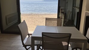 Une pièce avec une table et des chaises, une vue sur la plage et une porte donnant sur l’extérieur.