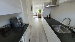 A modern kitchen with a built-in espresso machine, a stainless steel sink, and a view into the dining area.