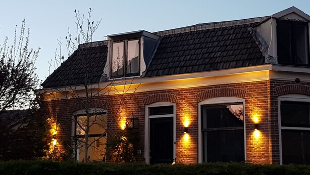 A two-story building with a brick facade, multiple garage doors, and a sloped roof.