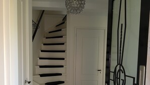 A staircase with a modern design, a door with a geometric metal design, and a chandelier.