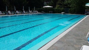 Ein Schwimmbecken mit klarem, blauem Wasser, gekennzeichneten Bahnen und Liegestühlen am Rand.