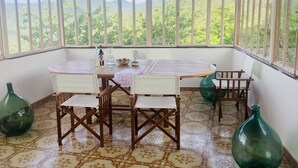 A room with a round wooden table, four chairs, a small potted plant, and two green glass vases.