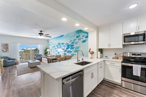 Una cocina moderna con armarios blancos, electrodomésticos de acero inoxidable y una isla grande con un lavamanos.