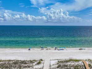 A beach with clear blue water, white sand, and a wooden boardwalk leading to the shore. - Golf Cart, Beach Access, Pool, Hot Tub (Mexico Beach)
