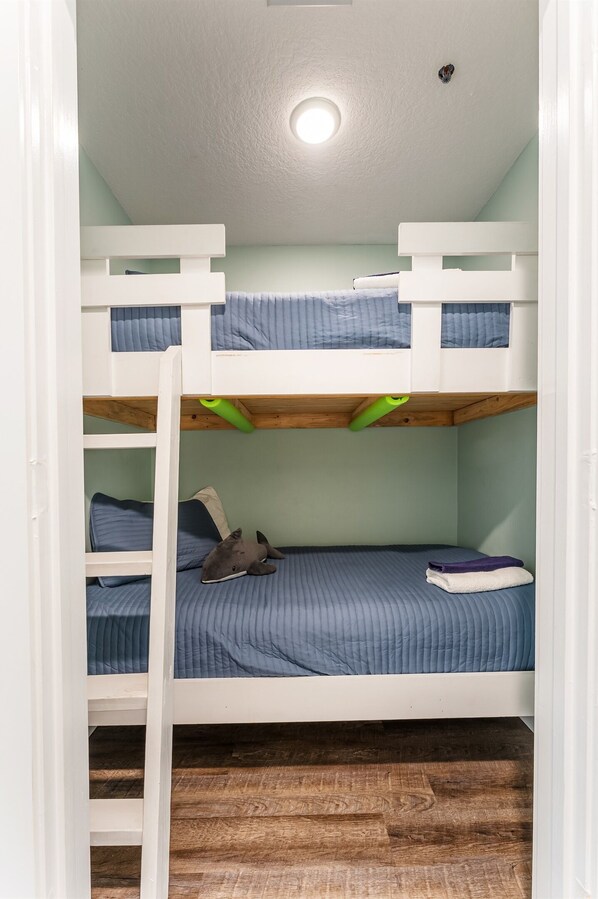 A bunk bed room with a wooden ladder, a ceiling light, and a window. - Golf Cart, Beach Access, Pool, Hot Tub (Mexico Beach)