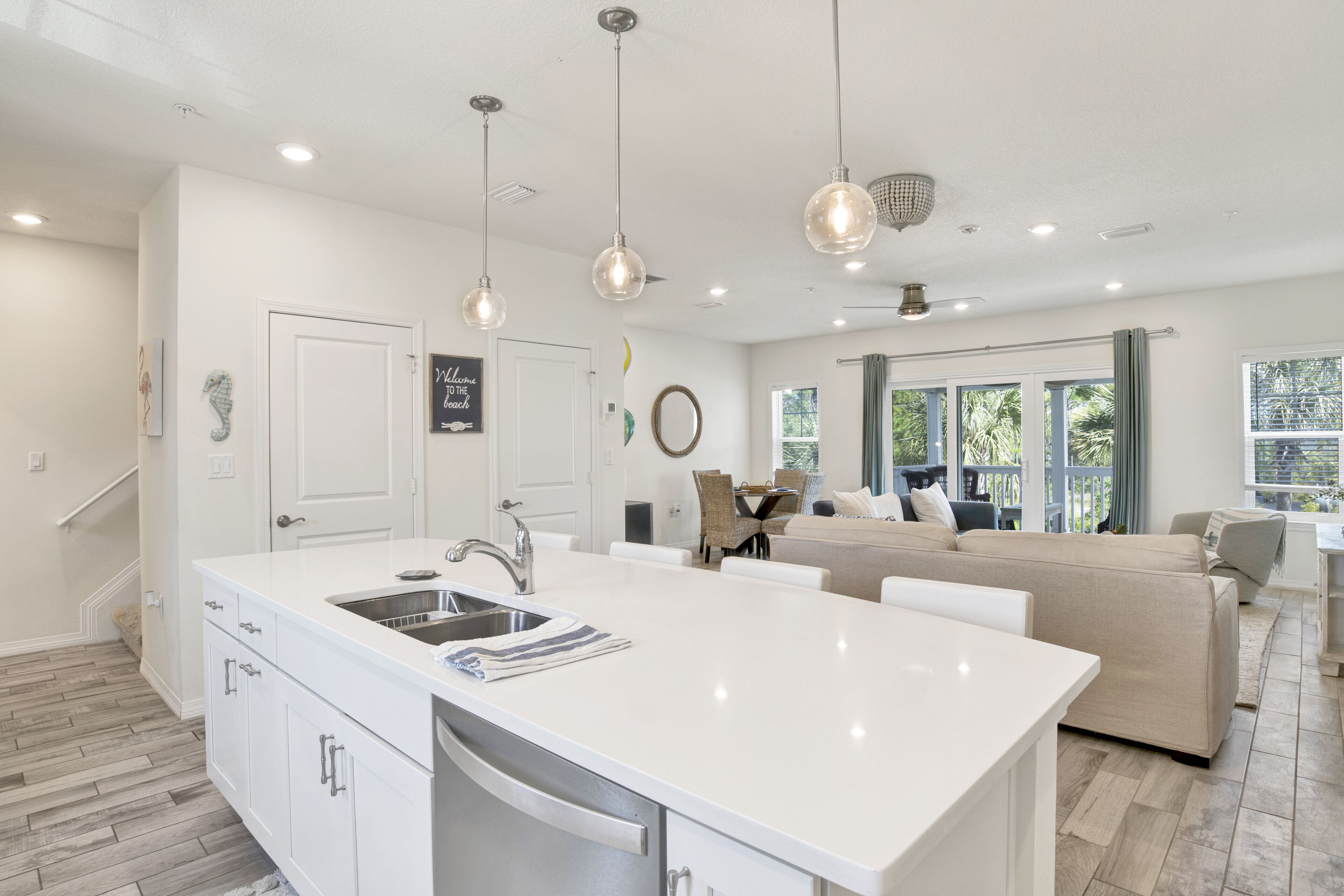 A modern kitchen with a large island, white cabinetry, and pendant lighting.