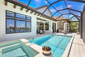A swimming pool with a hot tub, outdoor seating, and a view of the water.