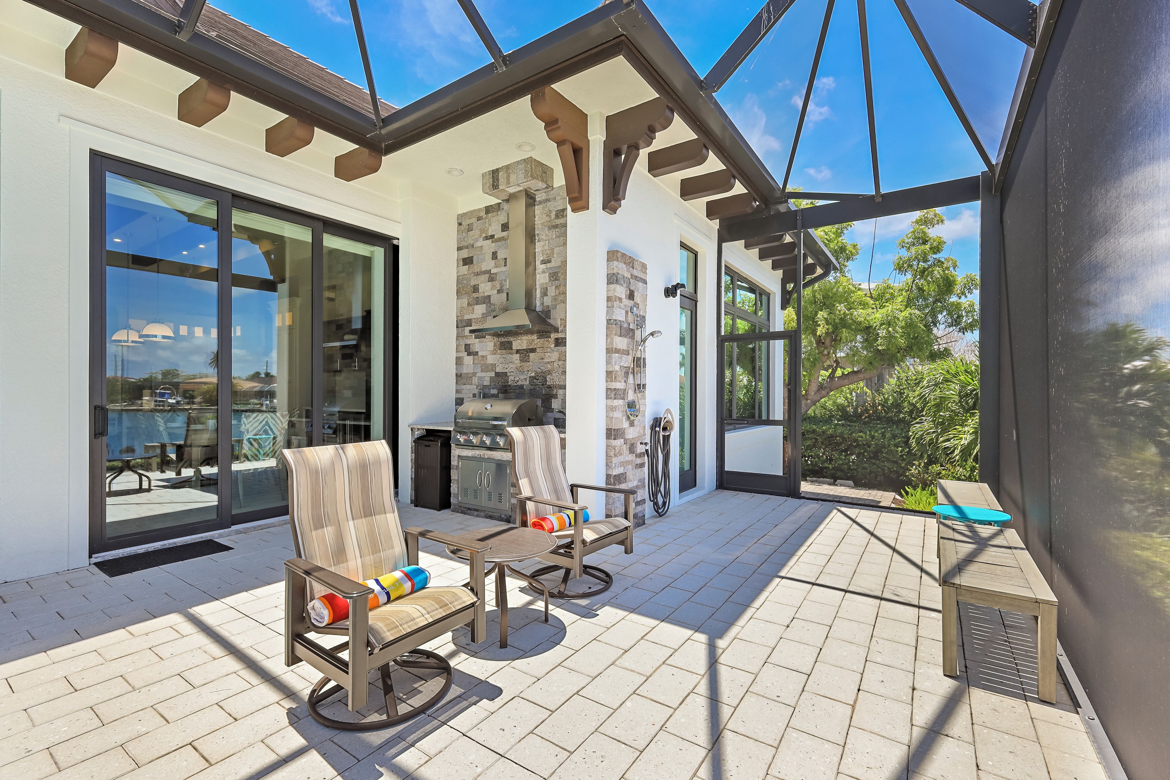 A covered patio with outdoor furniture, a grill, and a view of the surrounding landscape.